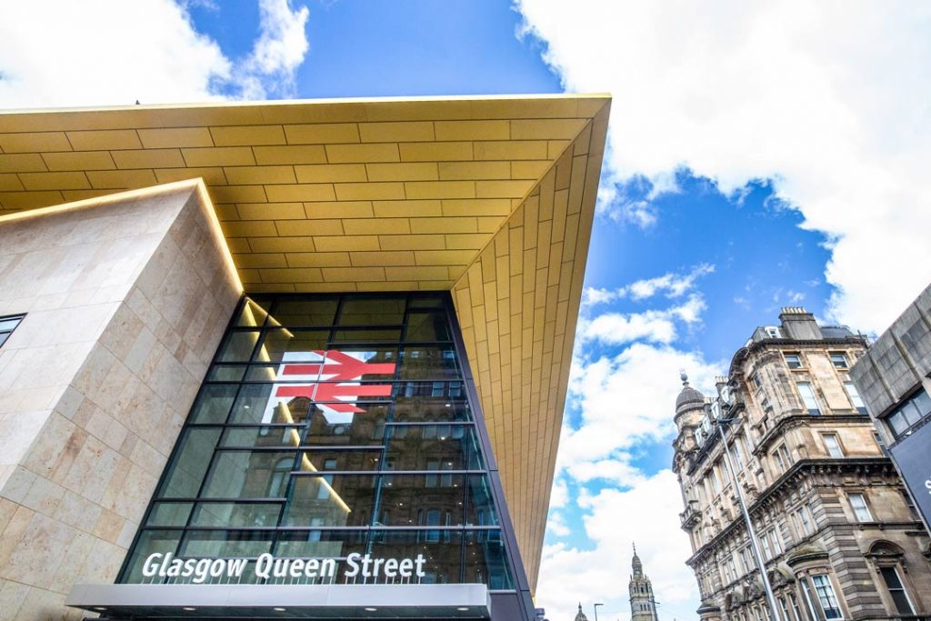 Construction photograph showing gold canopy of queen street railway station next to classic Glaswegian architecture