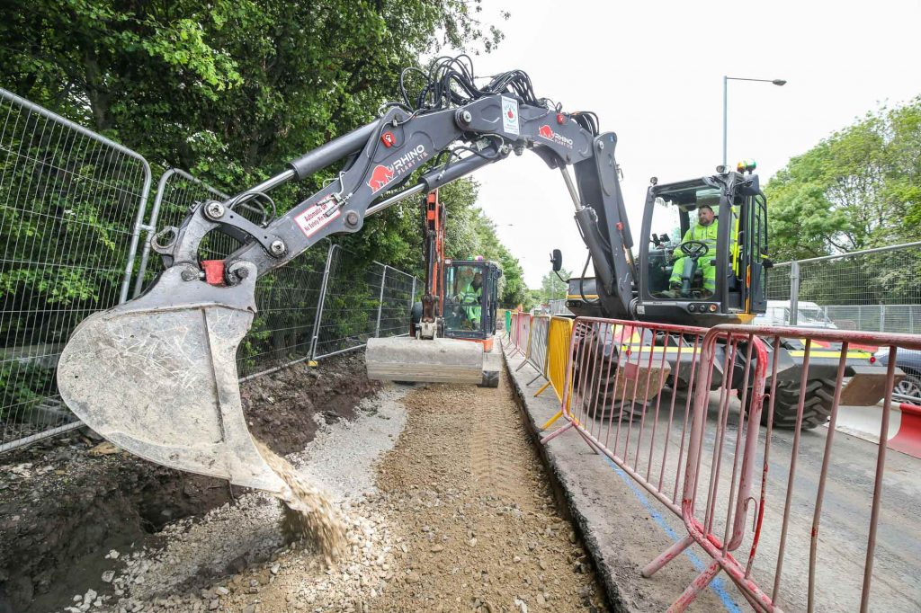 Image of Construction Site Digger laying dolomite on road expansion project in Birmingham. 