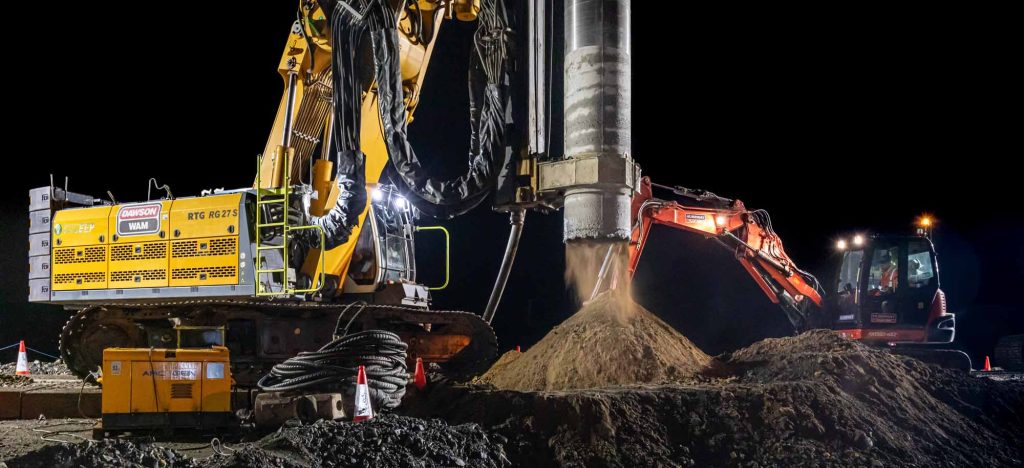 A1 Birtley Coalhouse extension night piling operations showing Dawson Wam RTG R627S boring machine extracting earth from highway foundation hole