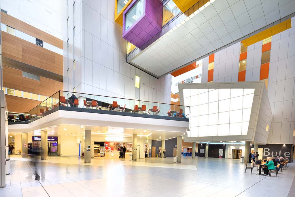 Queen Elizabeth University Hospital Glasgow interior atrium showing modern healthcare architecture with colorful ceiling elements and multi-level patient areas
