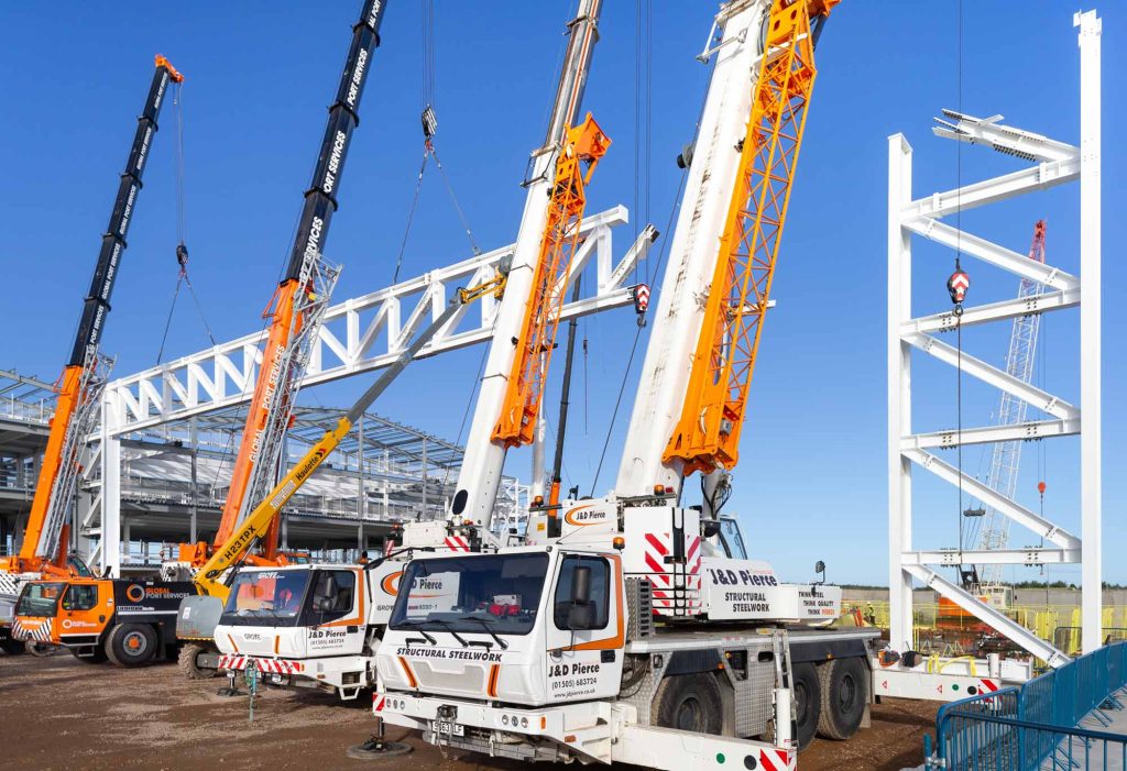 RAF Lossiemouth Atlantic Building construction showing multiple J&D Pierce cranes erecting white steel framework for Royal Air Force aviation infrastructure
